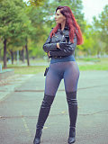 In an autumn park, the redheaded girl named Jeny removes her skirt to pose seductively in her seamless blue pantyhose, wearing only a leather jacket and high boots